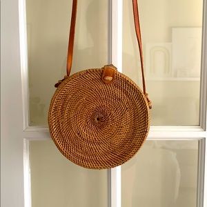 round rattan bag with crossbody strap.